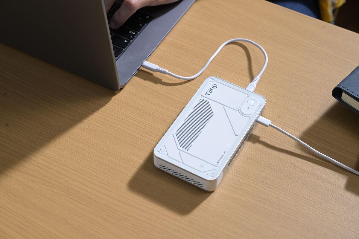 TiinyAI Pocket Lab product photo showing the device tethered to a laptop and external power