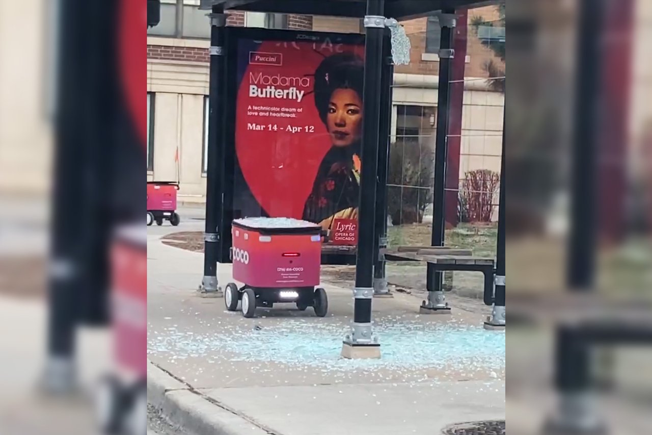 Coco delivery robot surrounded by shattered glass at a Chicago bus shelter