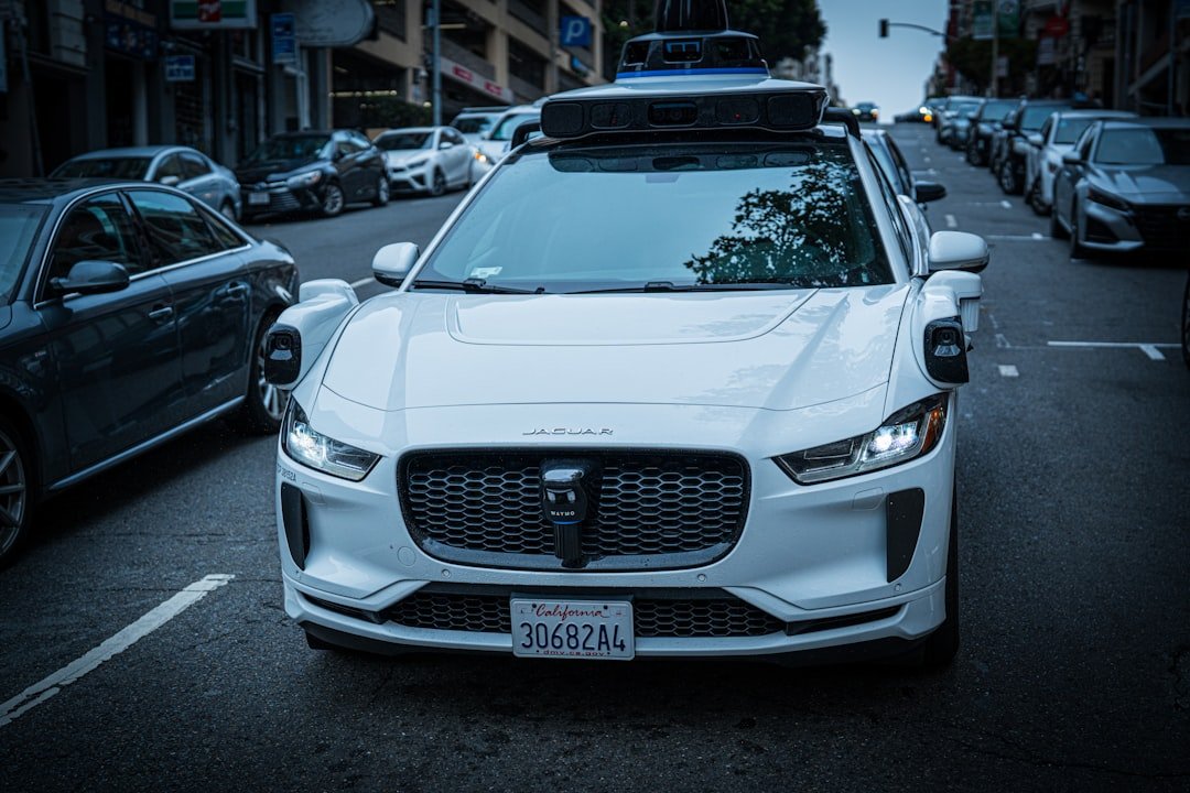 White Waymo autonomous self-driving vehicle operating without a human driver — illustrating the lack of manual passenger override