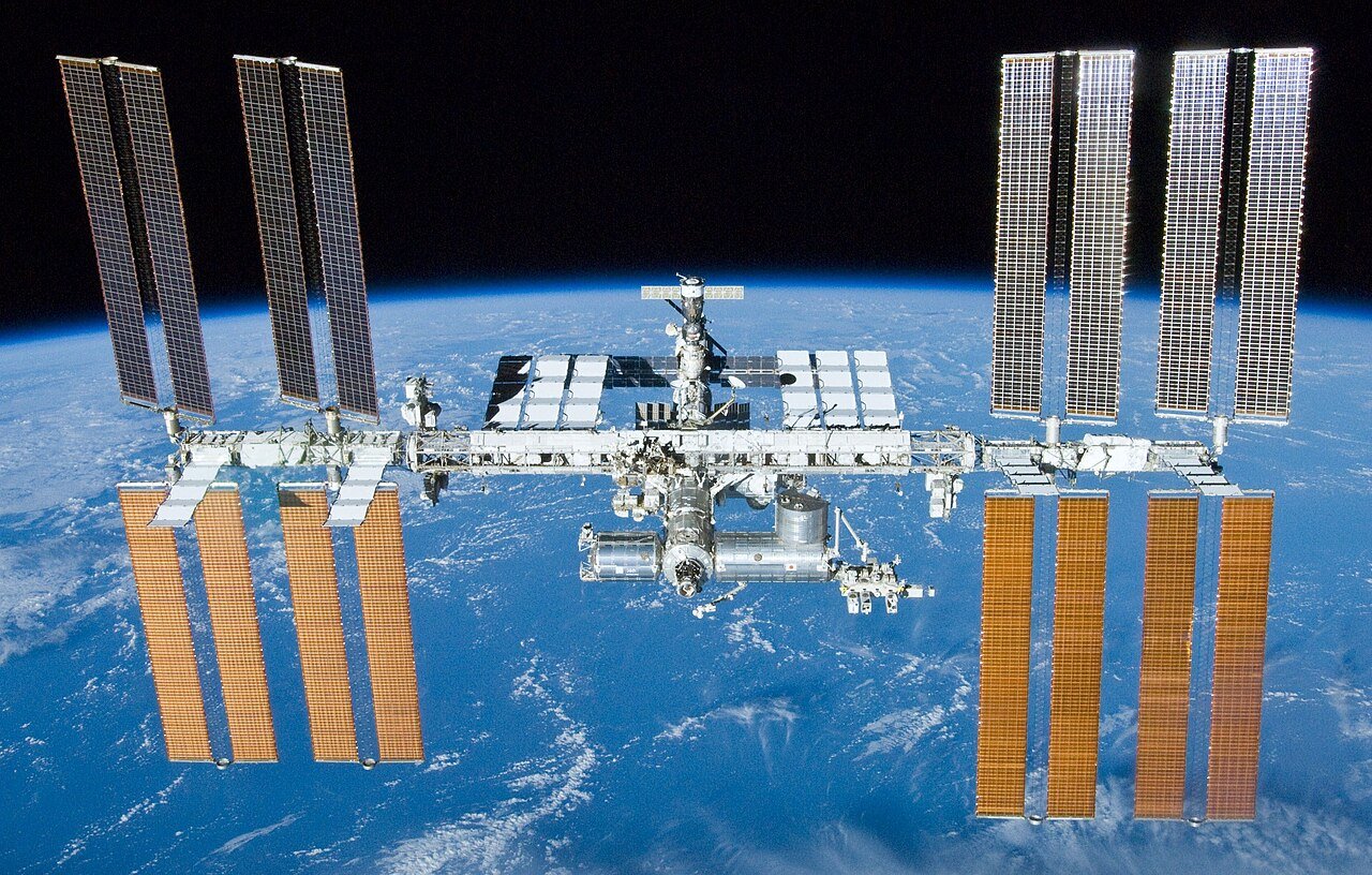 International Space Station in orbit — at 109 meters wide, it took 13 years to assemble and is already smaller than the solar arrays proposed for orbital AI data centers