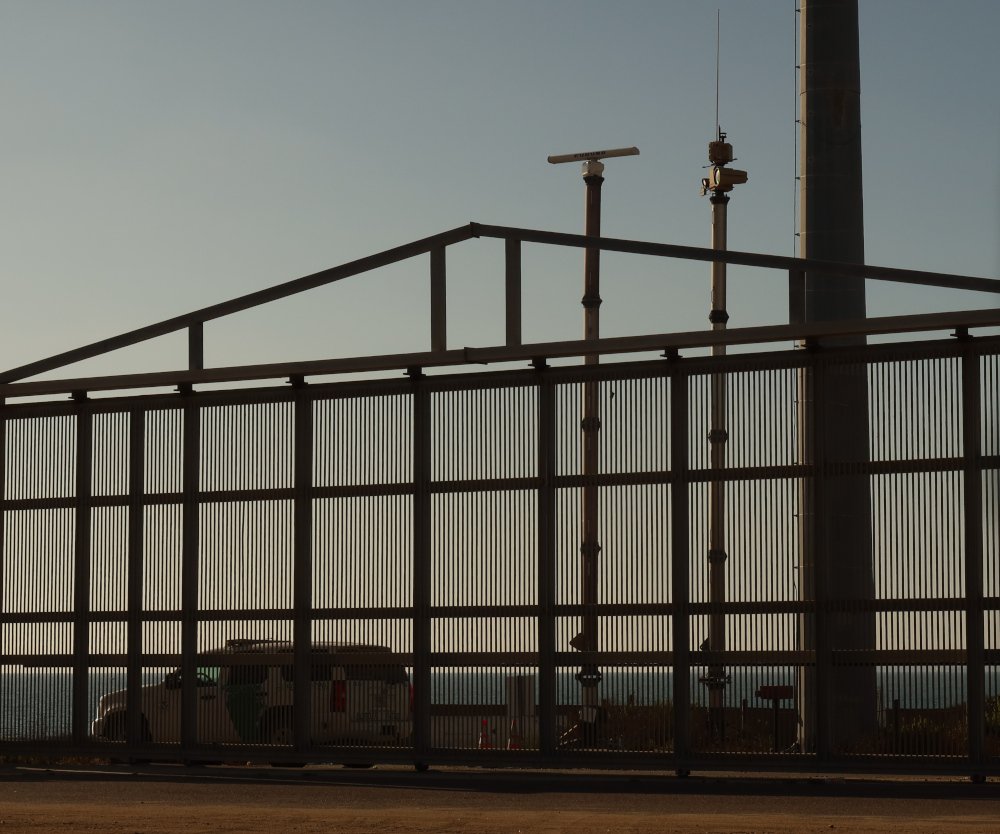 Anduril Maritime Sentry AI surveillance tower at the San Diego border fence alongside a CBP Border Patrol vehicle